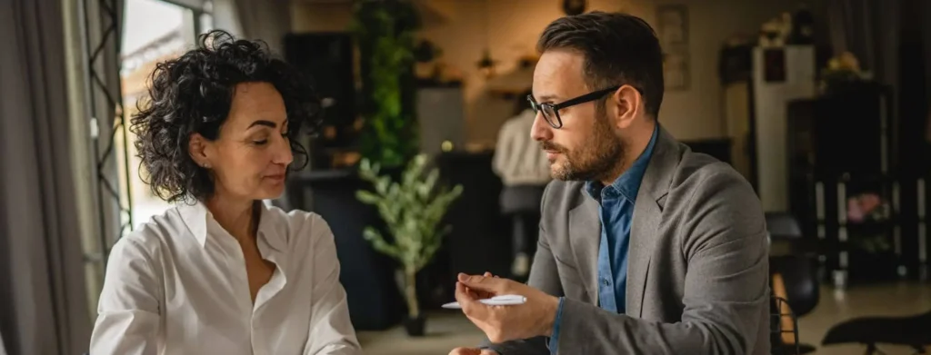 A male solicitor discusses director disqualification proceedings with a female director in a professional office. The conversation highlights legal advice on managing disqualification risks. This image represents expert guidance on director disqualification.